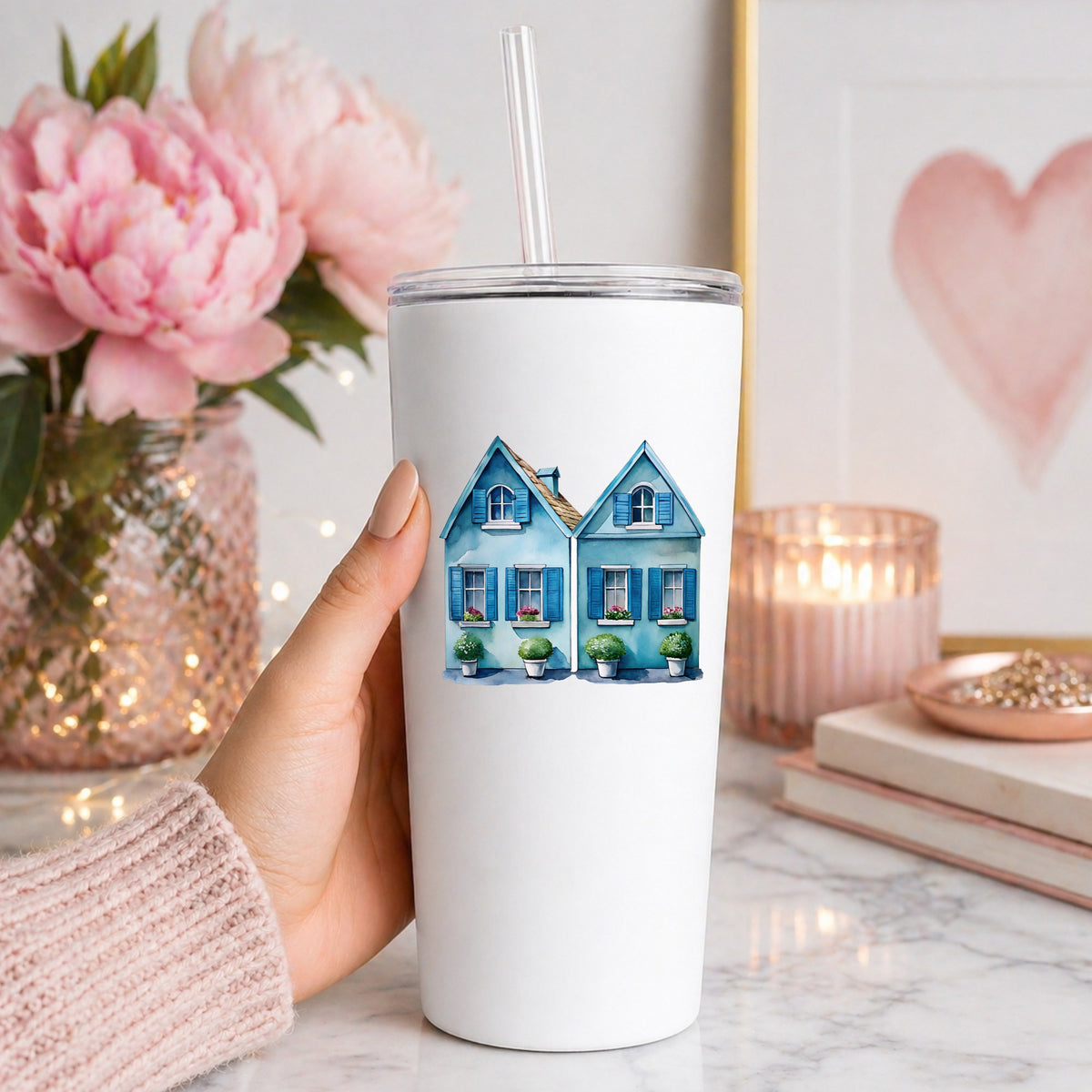 Two Blue Coastal Cottages UV DTF sticker applied to a white straw tumbler beside pink peonies
