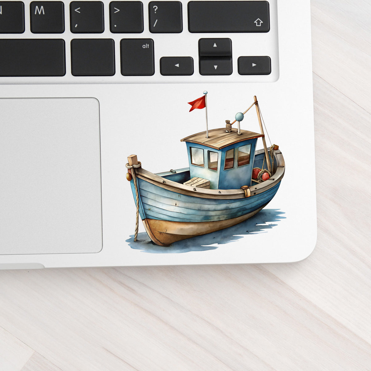 Wooden Fishing Boat With Red Flag UV DTF sticker applied to a silver laptop beside the keyboard
