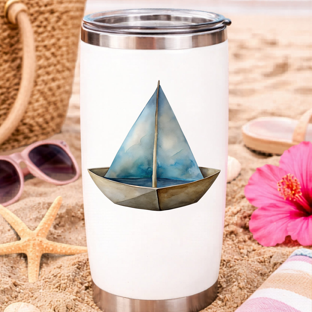 Paper Sailboat UV DTF sticker applied to a white travel tumbler on beach sand