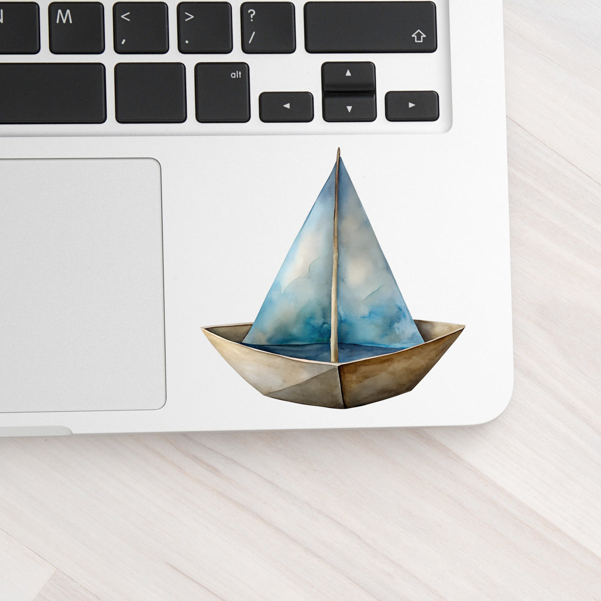 Paper Sailboat UV DTF sticker applied to a silver laptop beside the keyboard