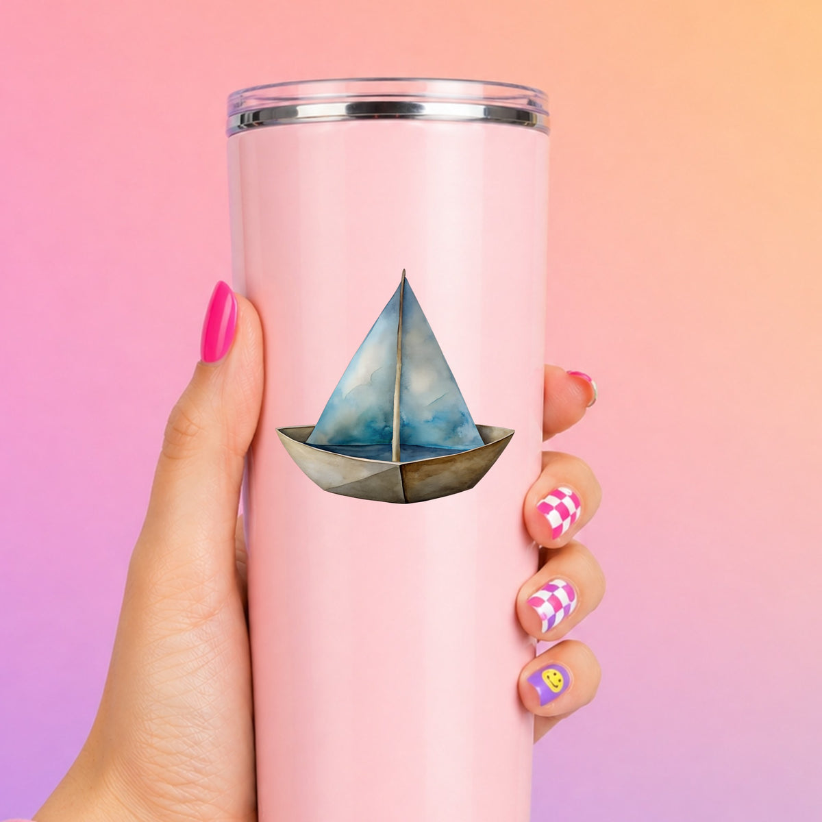 Paper Sailboat UV DTF sticker applied to a tall pink tumbler on a pink and orange background
