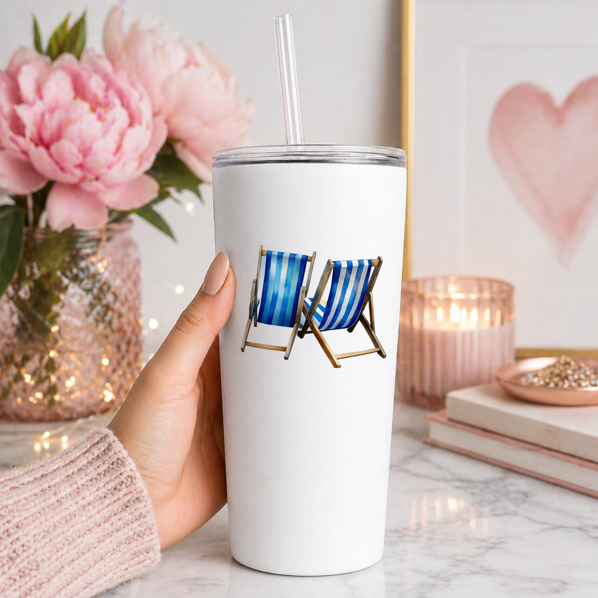 Two Blue Striped Beach Chairs UV DTF sticker applied to a white straw tumbler beside pink peonies