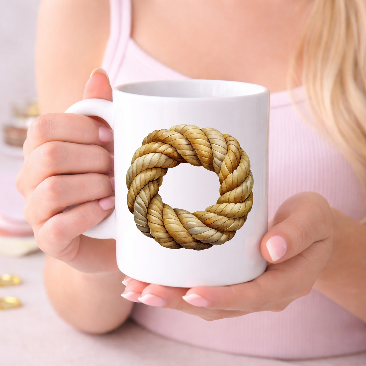 Rope Knot Wreath UV DTF sticker applied to a white coffee mug held in both hands
