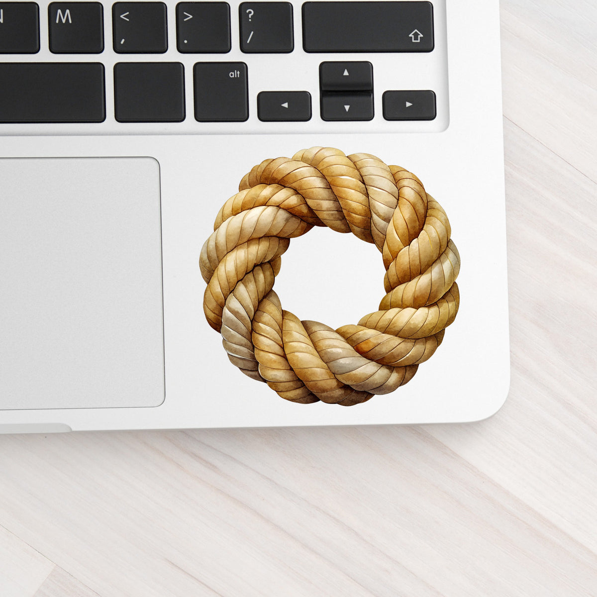 Rope Knot Wreath UV DTF sticker applied to a silver laptop beside the keyboard