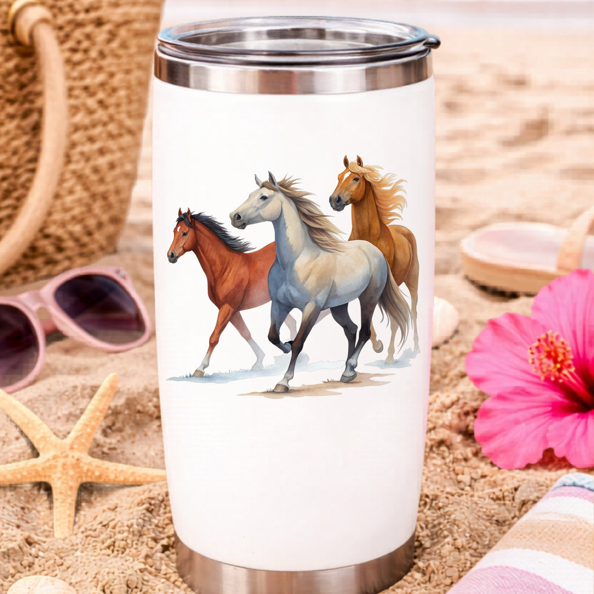 Three Horses Running UV DTF sticker applied to a white travel tumbler on beach sand