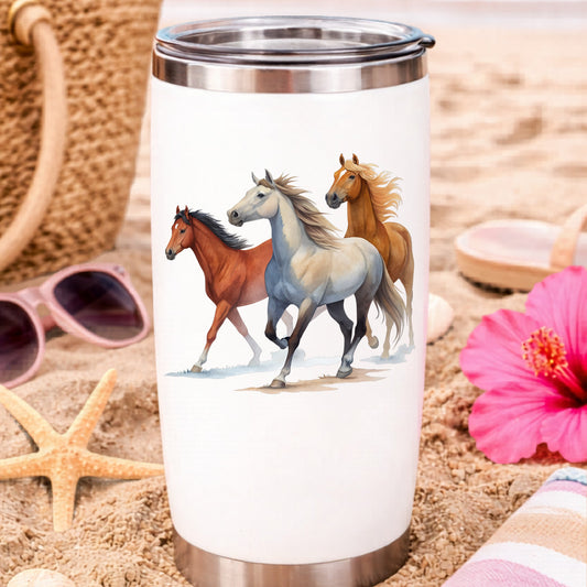 Three Horses Running UV DTF sticker applied to a white travel tumbler on beach sand