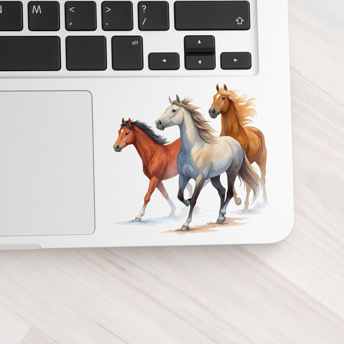 Three Horses Running UV DTF sticker applied to a silver laptop beside the keyboard