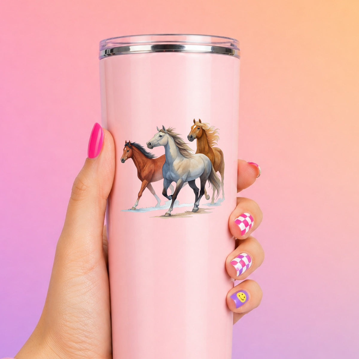 Three Horses Running UV DTF sticker applied to a tall pink tumbler on a pink and orange background