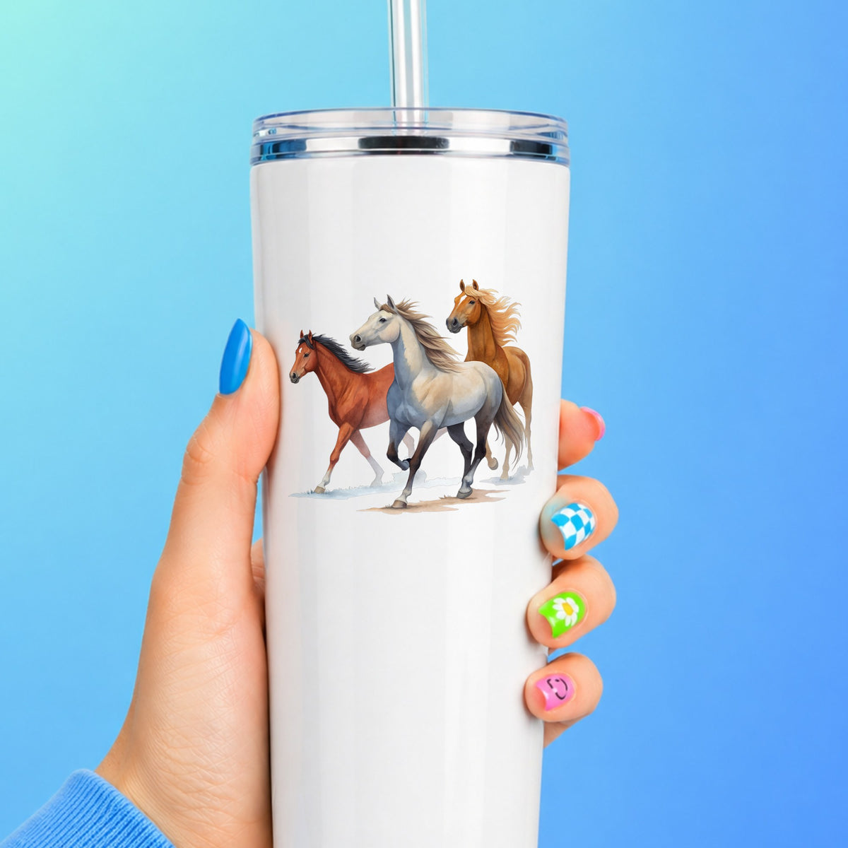 Three Horses Running UV DTF sticker applied to a white straw tumbler on a blue background
