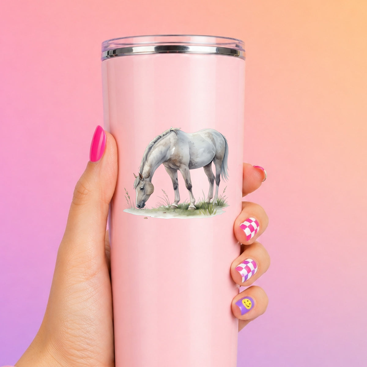 Gray Horse Grazing On Grass UV DTF sticker applied to a tall pink tumbler on a pink and orange background