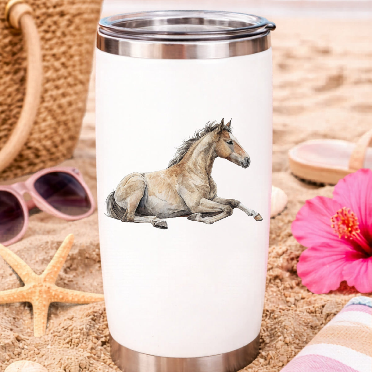 Buckskin Foal Lying Down UV DTF sticker applied to a white travel tumbler on beach sand