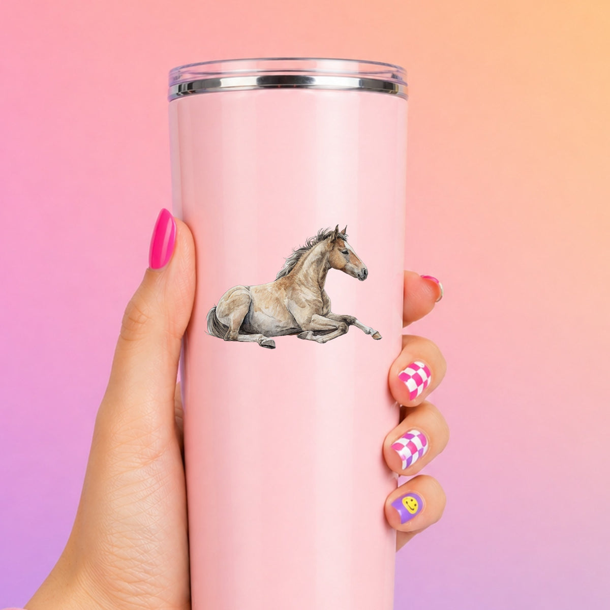 Buckskin Foal Lying Down UV DTF sticker applied to a tall pink tumbler on a pink and orange background