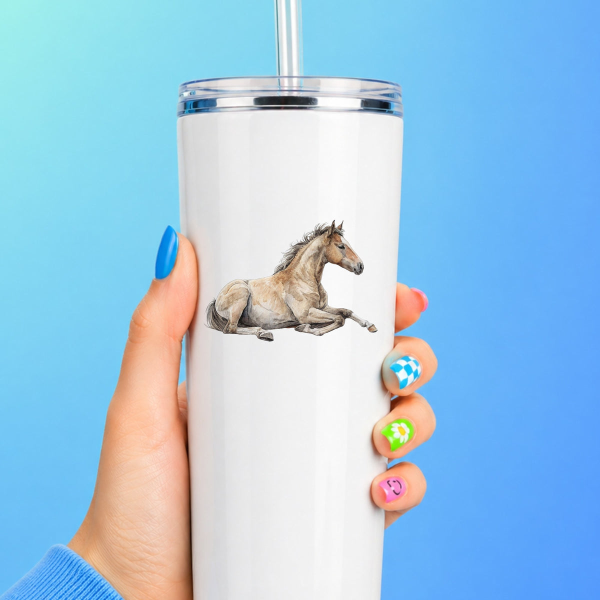 Buckskin Foal Lying Down UV DTF sticker applied to a white straw tumbler on a blue background