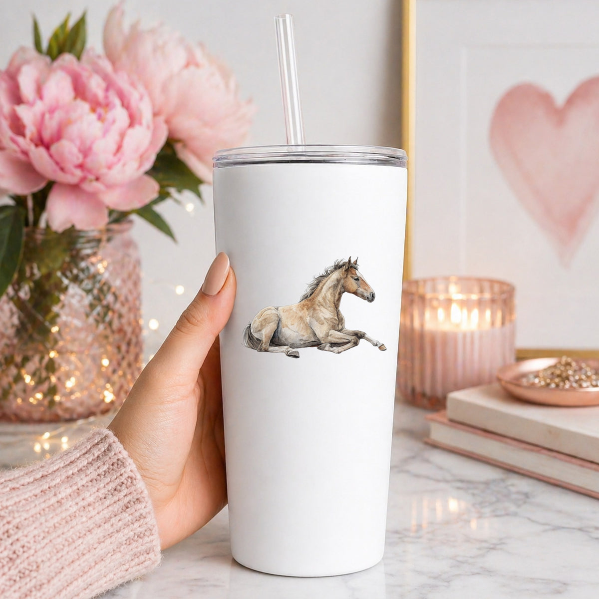 Buckskin Foal Lying Down UV DTF sticker applied to a white straw tumbler beside pink peonies