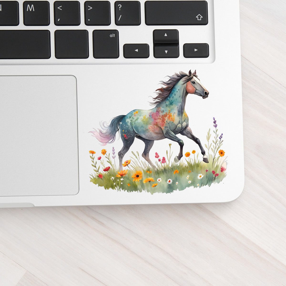 Floral Horse Running Through Wildflowers UV DTF sticker applied to a silver laptop beside the keyboard