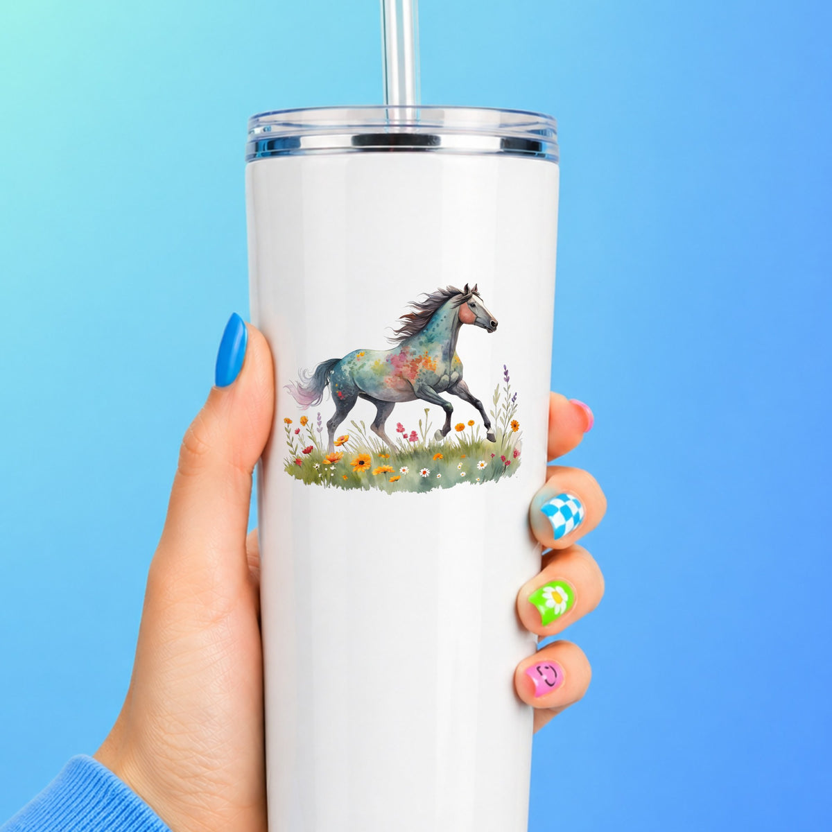 Floral Horse Running Through Wildflowers UV DTF sticker applied to a white straw tumbler on a blue background
