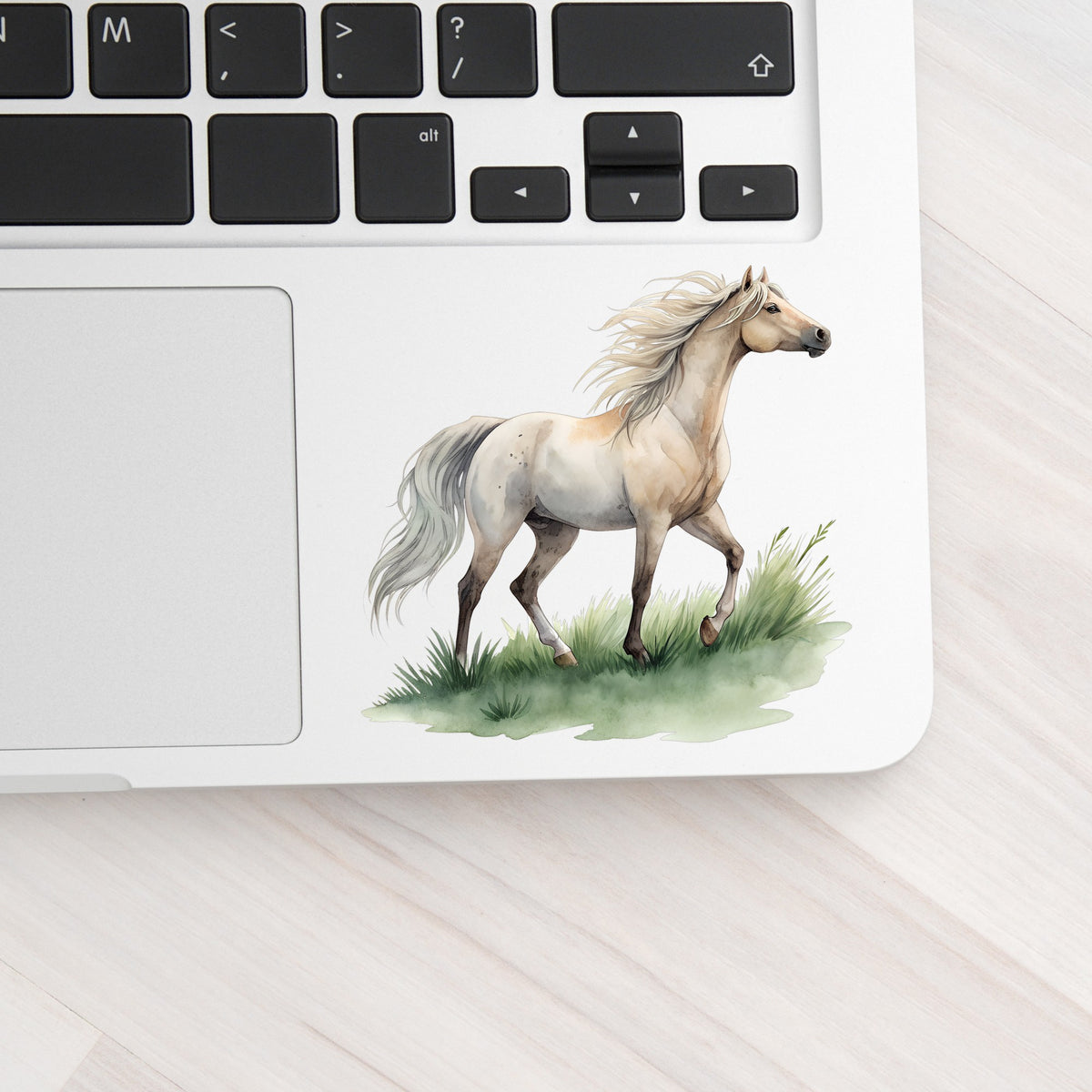 Cream Horse Trotting On Grass UV DTF sticker applied to a silver laptop beside the keyboard