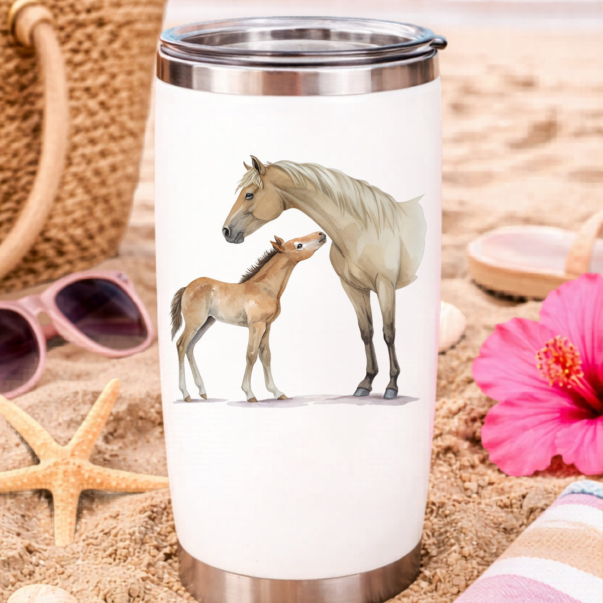 Mare Nuzzling Foal UV DTF sticker applied to a white travel tumbler on beach sand