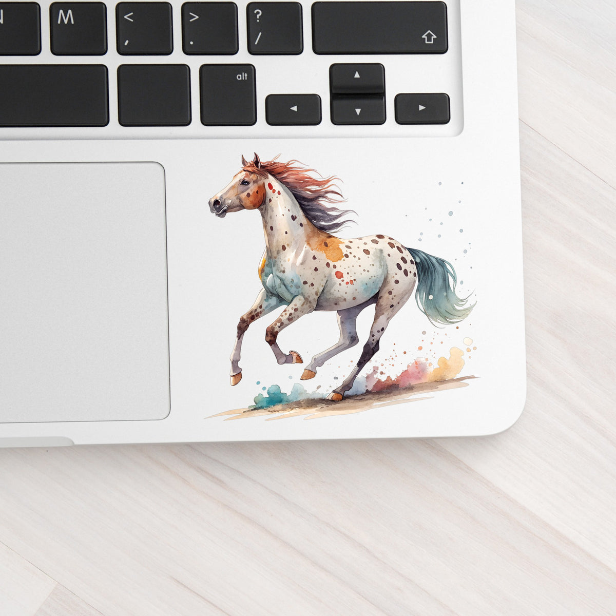 Appaloosa Spotted Horse Running UV DTF sticker applied to a silver laptop beside the keyboard