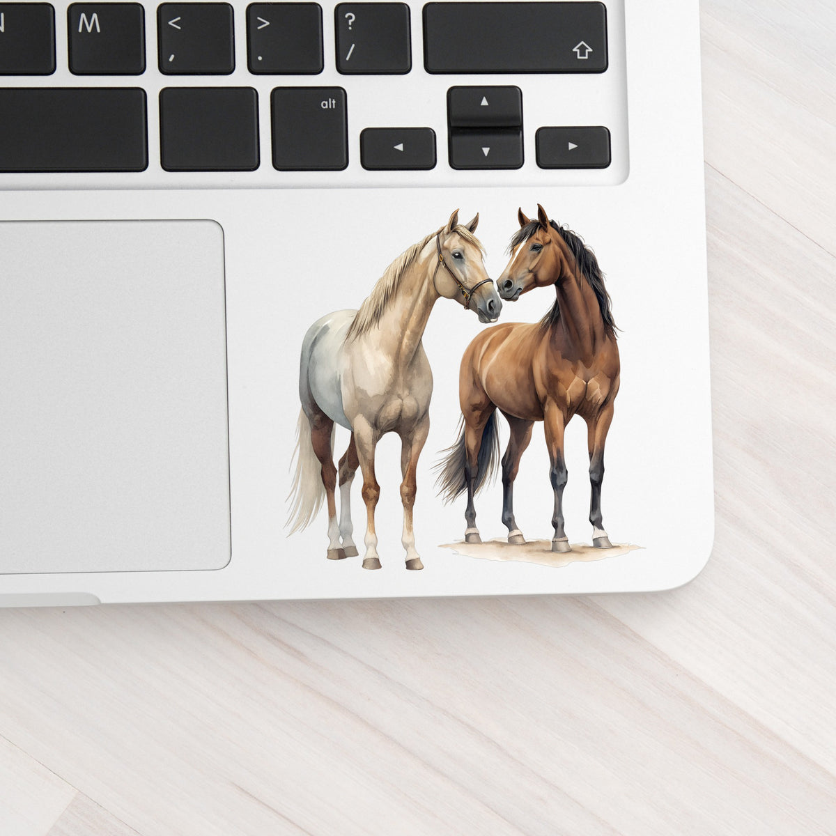 Two Horses Touching Noses UV DTF sticker applied to a silver laptop beside the keyboard
