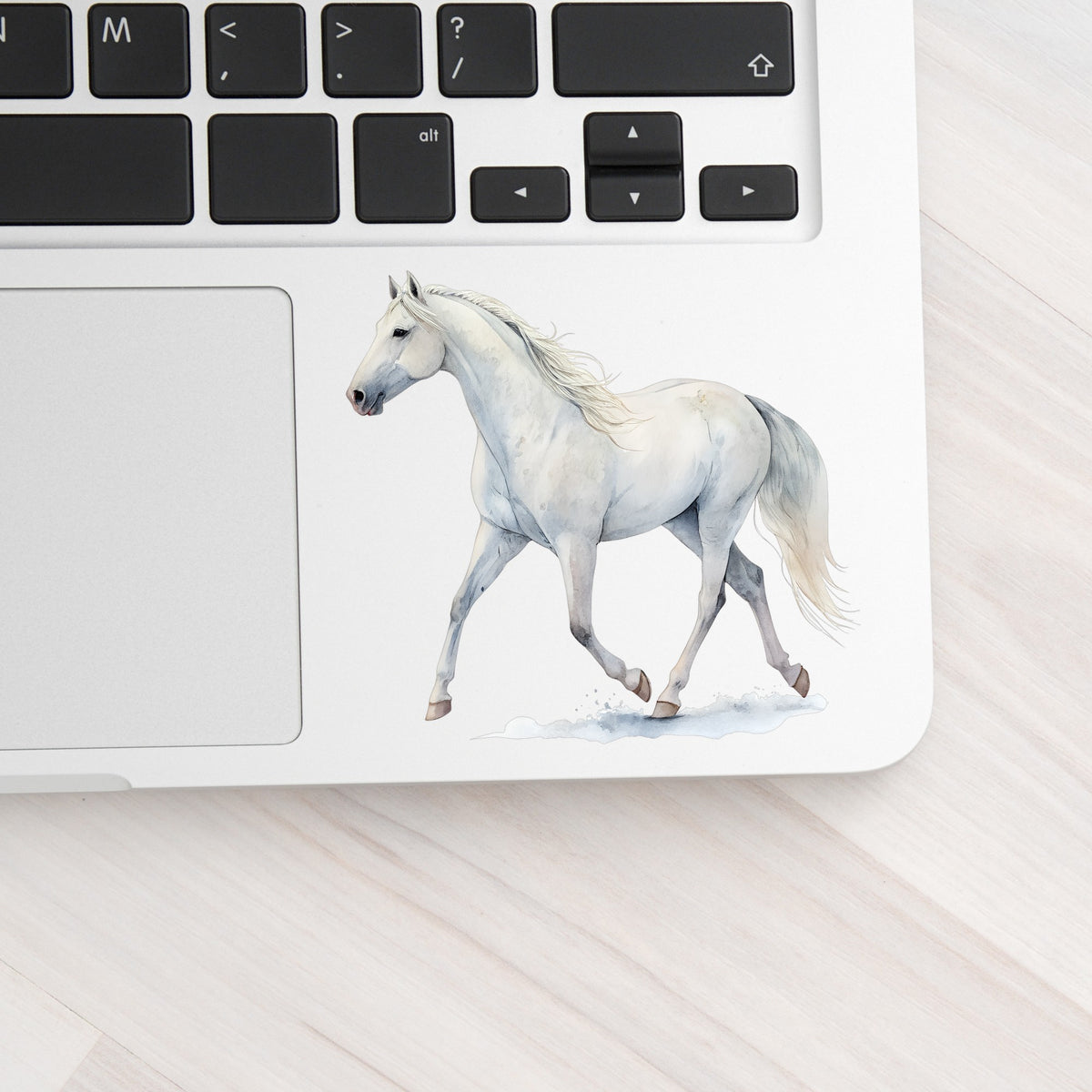 White Horse Walking UV DTF sticker applied to a silver laptop beside the keyboard