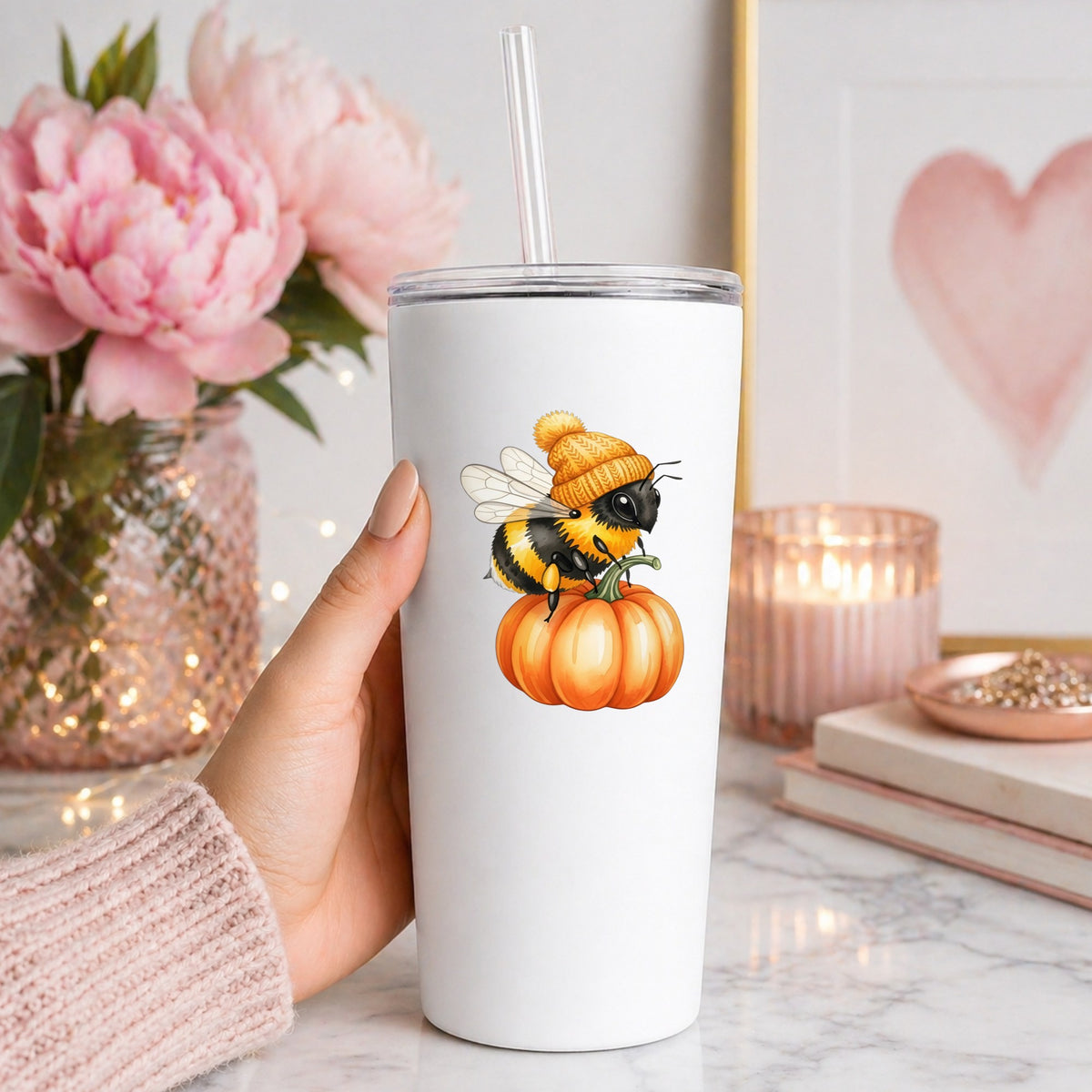 Bee In Orange Beanie On Pumpkin UV DTF sticker applied to a white straw tumbler beside pink peonies