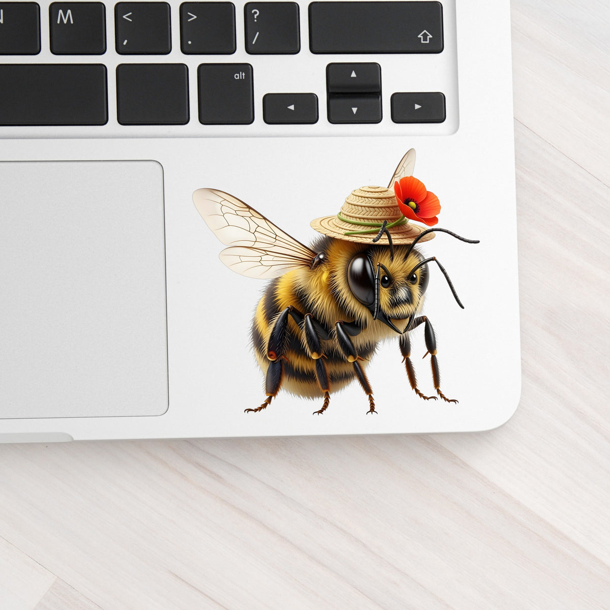 Bee In Straw Hat With Red Poppy UV DTF sticker applied to a silver laptop beside the keyboard