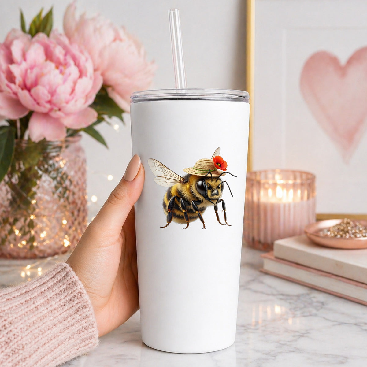 Bee In Straw Hat With Red Poppy UV DTF sticker applied to a white straw tumbler beside pink peonies