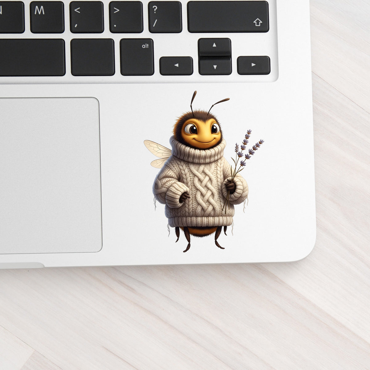 Bee In Cable Knit Sweater With Lavender UV DTF sticker applied to a silver laptop beside the keyboard