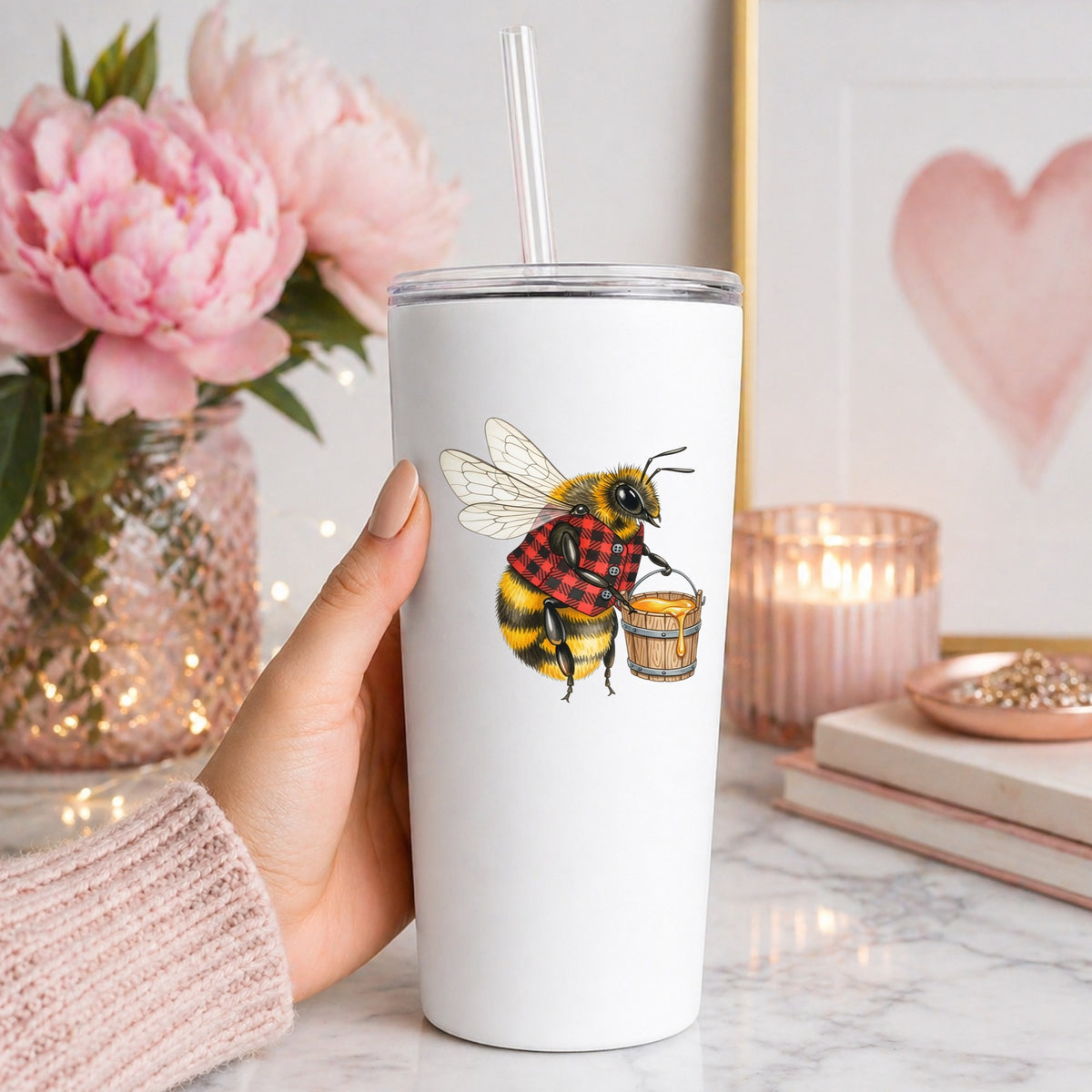 Bee In Plaid Vest With Honey Bucket UV DTF sticker applied to a white straw tumbler beside pink peonies