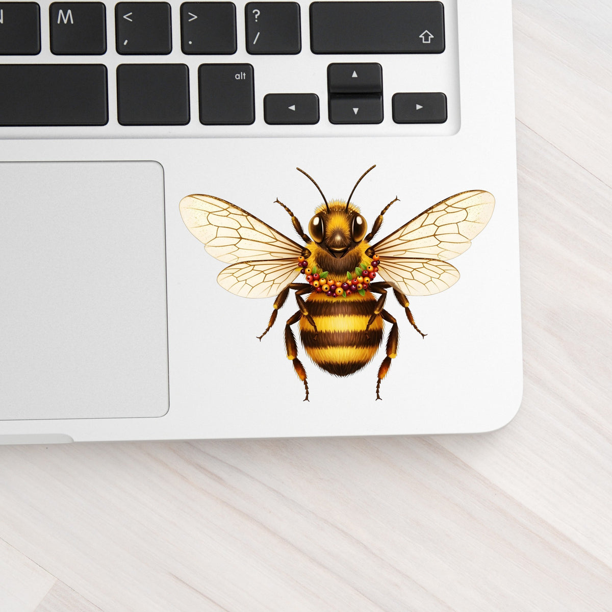 Bee With Berry Garland Necklace UV DTF sticker applied to a silver laptop beside the keyboard