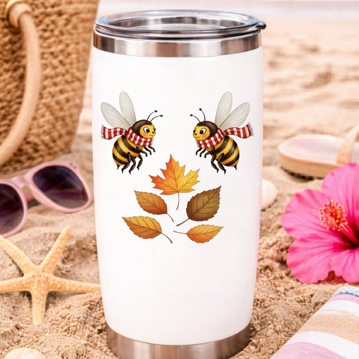 Two Bees With Autumn Leaves UV DTF sticker applied to a white travel tumbler on beach sand