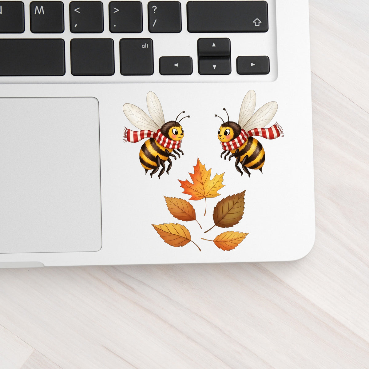Two Bees With Autumn Leaves UV DTF sticker applied to a silver laptop beside the keyboard