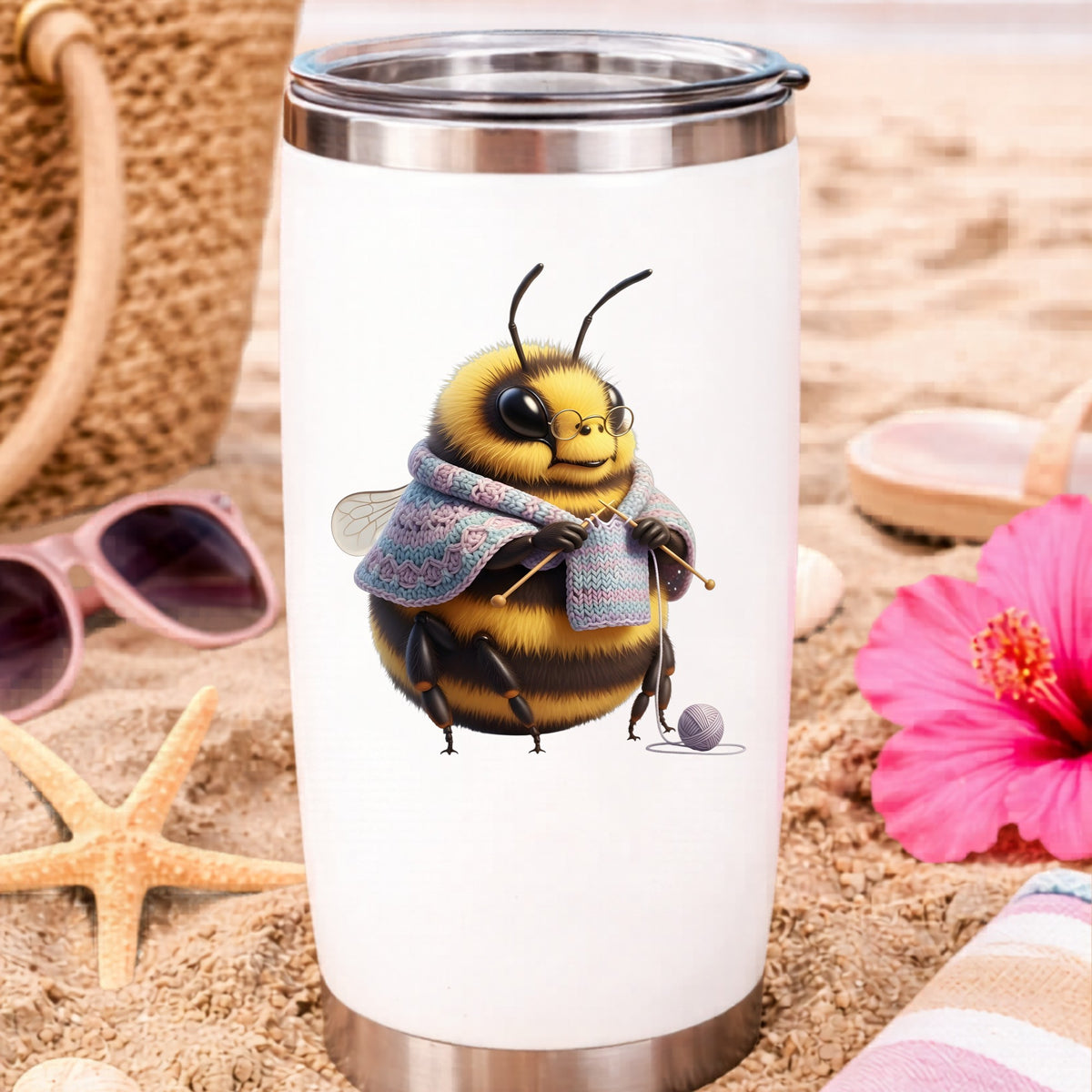 Bee Knitting In Shawl UV DTF sticker applied to a white travel tumbler on beach sand