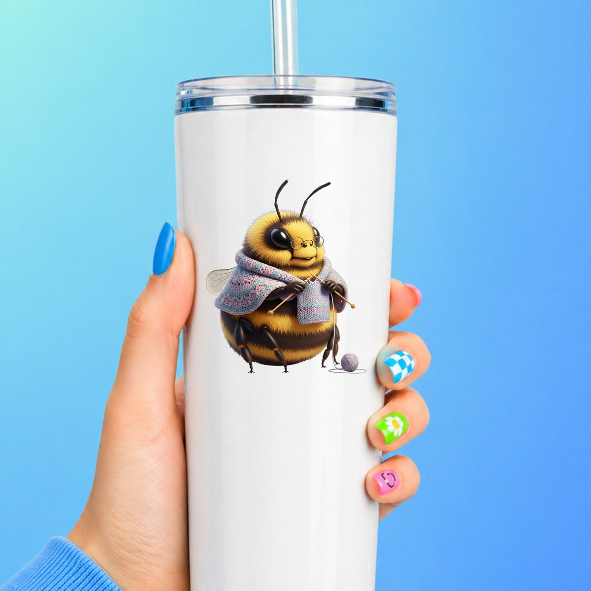 Bee Knitting In Shawl UV DTF sticker applied to a white straw tumbler on a blue background