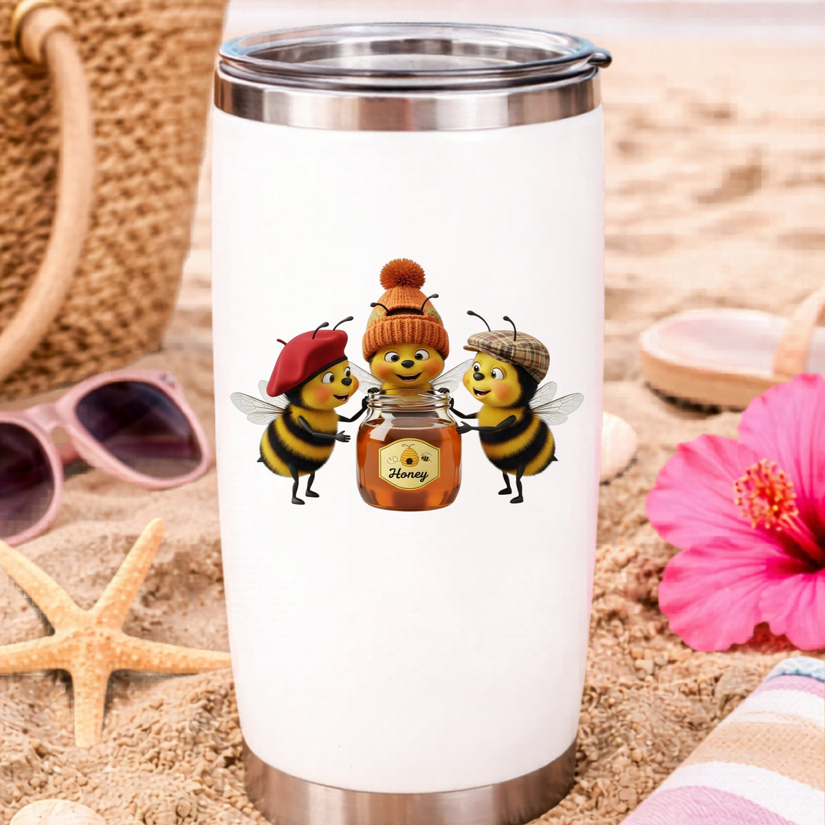 Three Bees With Honey Jar UV DTF sticker applied to a white travel tumbler on beach sand