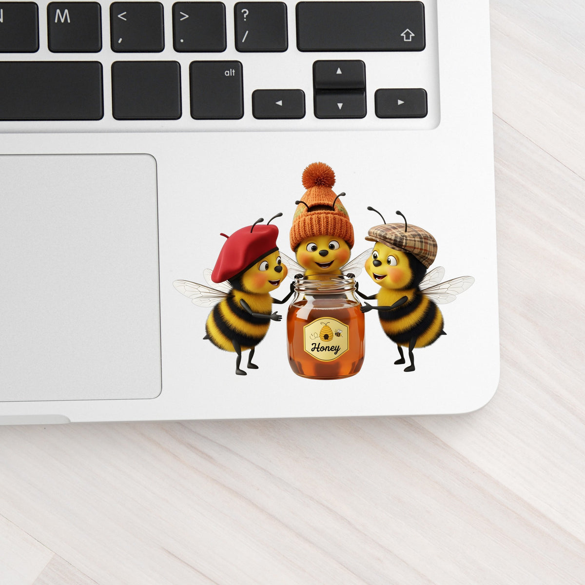 Three Bees With Honey Jar UV DTF sticker applied to a silver laptop beside the keyboard