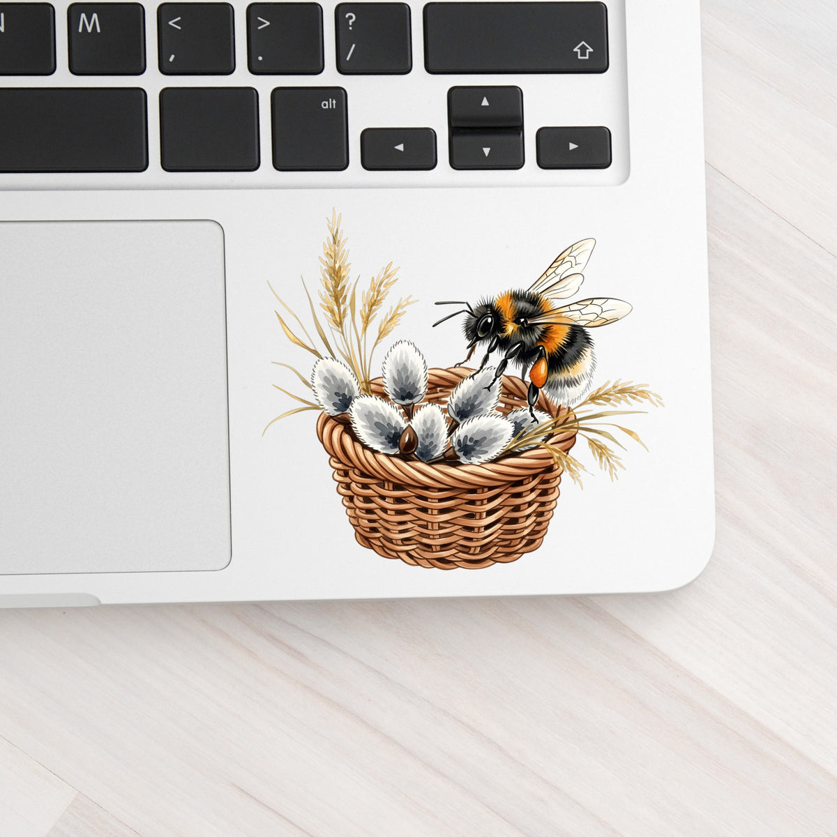 Bumble Bee On Basket Of Pussy Willow UV DTF sticker applied to a silver laptop beside the keyboard