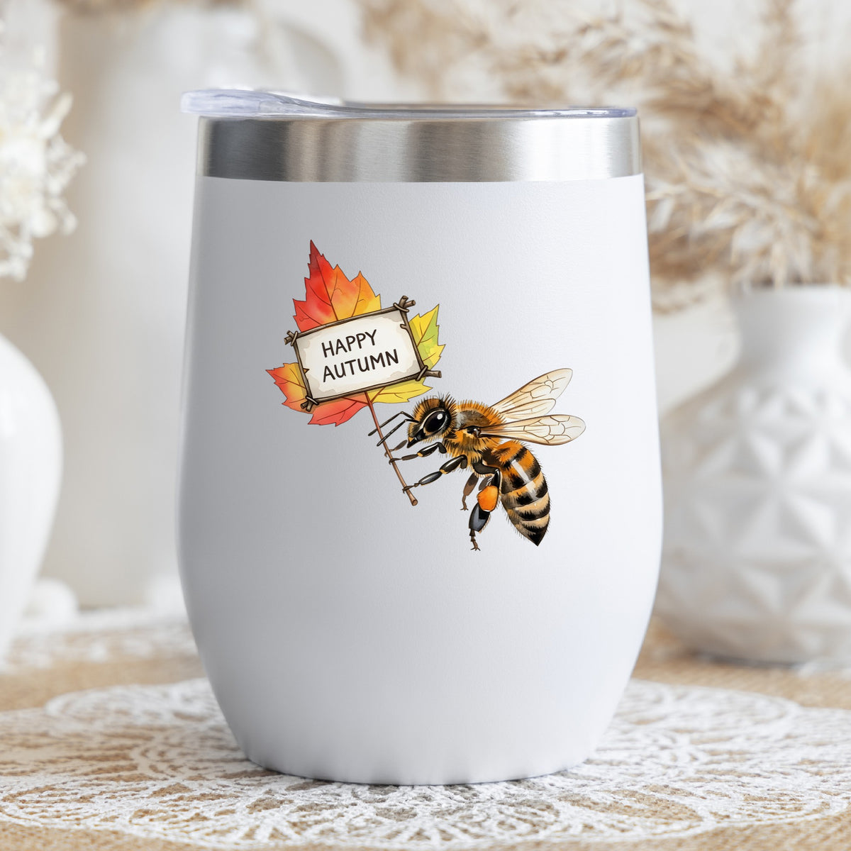 Honeybee Holding Happy Autumn Sign UV DTF sticker applied to a white stemless tumbler with a lid