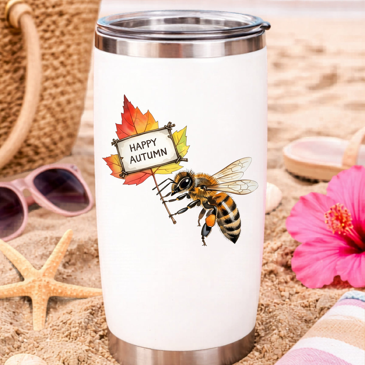 Honeybee Holding Happy Autumn Sign UV DTF sticker applied to a white travel tumbler on beach sand
