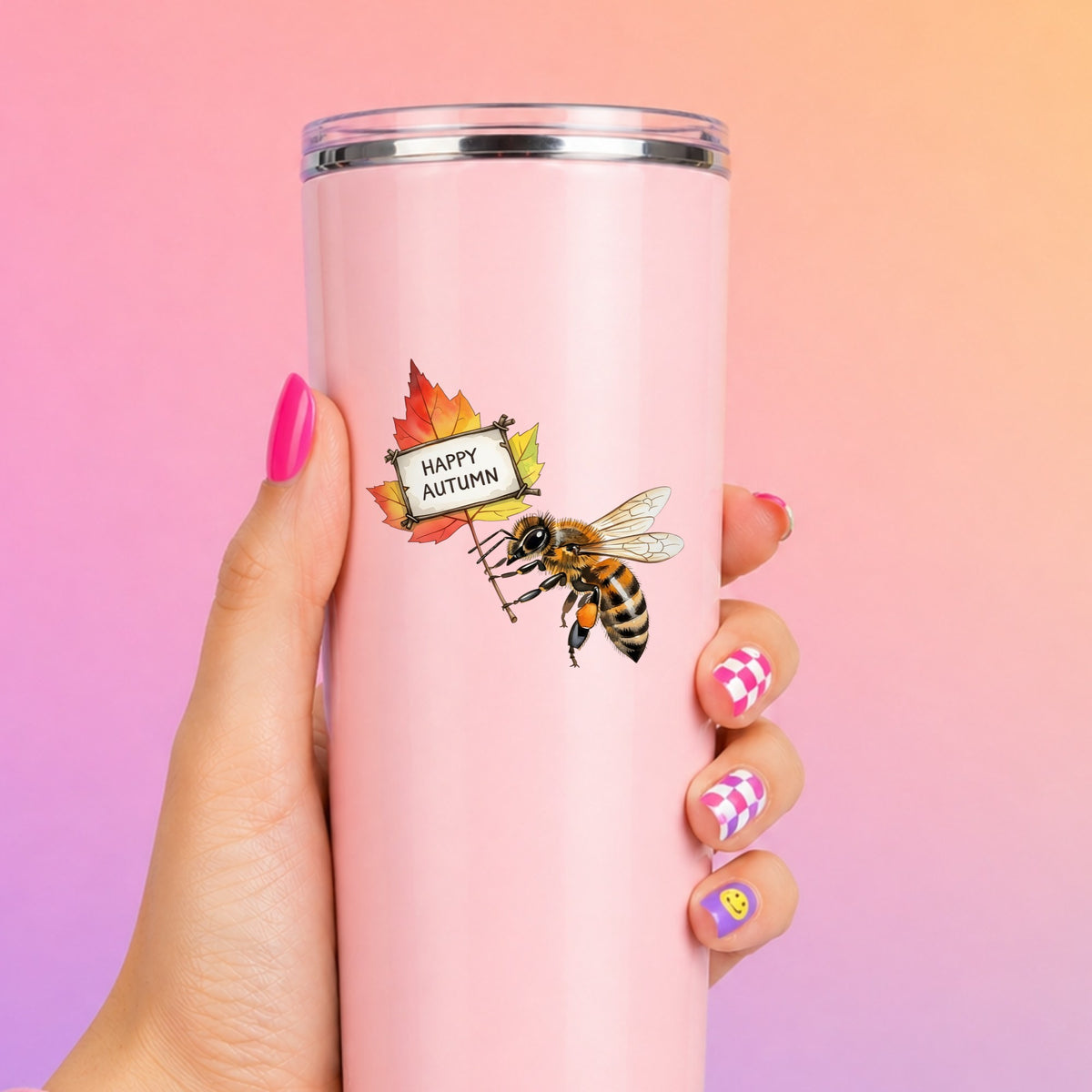 Honeybee Holding Happy Autumn Sign UV DTF sticker applied to a tall pink tumbler on a pink and orange background