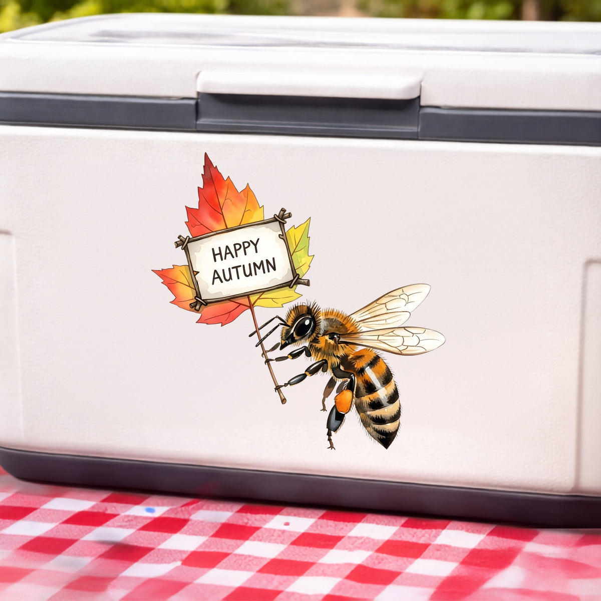 Honeybee Holding Happy Autumn Sign UV DTF sticker applied to a white cooler on a red gingham cloth