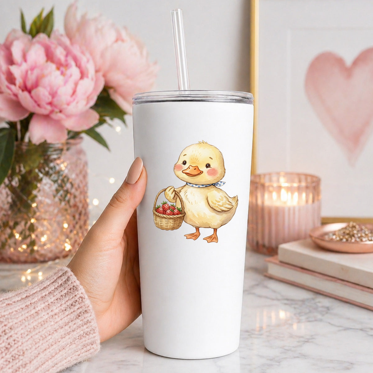 Duckling With Strawberry Basket UV DTF sticker applied to a white straw tumbler beside pink peonies