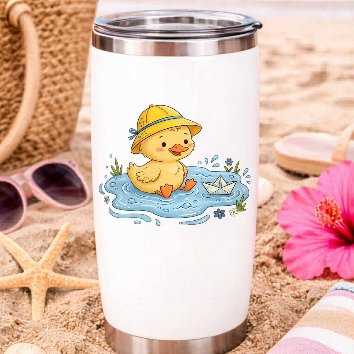 Duckling In Rain Hat In Puddle UV DTF sticker applied to a white travel tumbler on beach sand