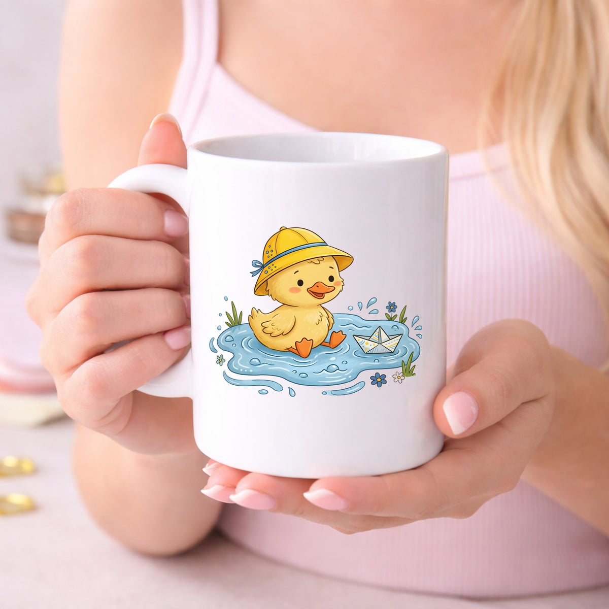 Duckling In Rain Hat In Puddle UV DTF sticker applied to a white coffee mug held in both hands