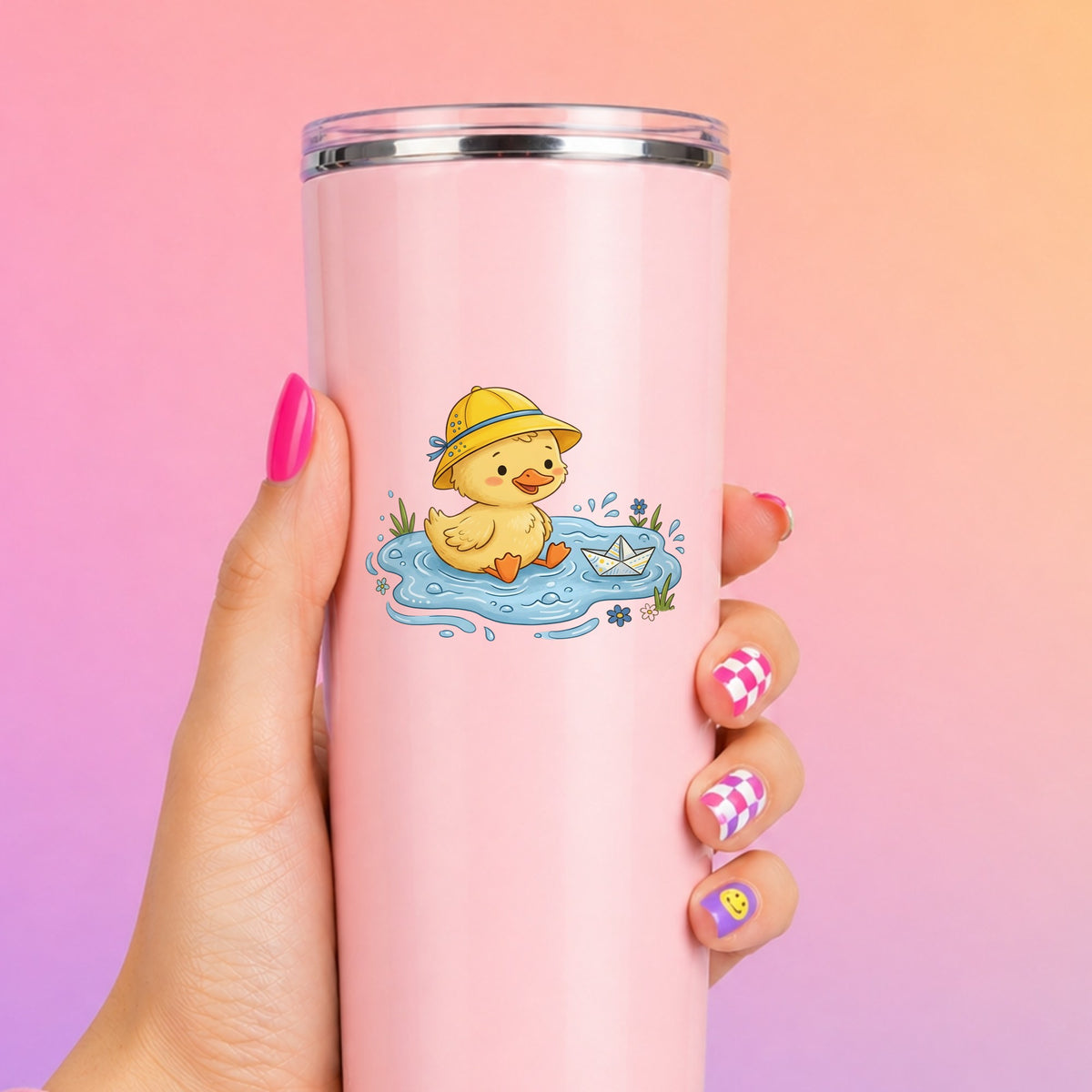 Duckling In Rain Hat In Puddle UV DTF sticker applied to a tall pink tumbler on a pink and orange background