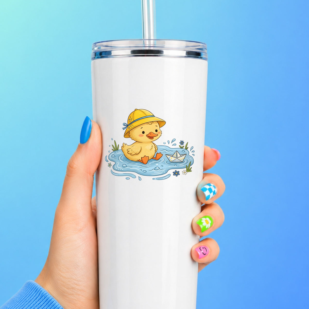 Duckling In Rain Hat In Puddle UV DTF sticker applied to a white straw tumbler on a blue background