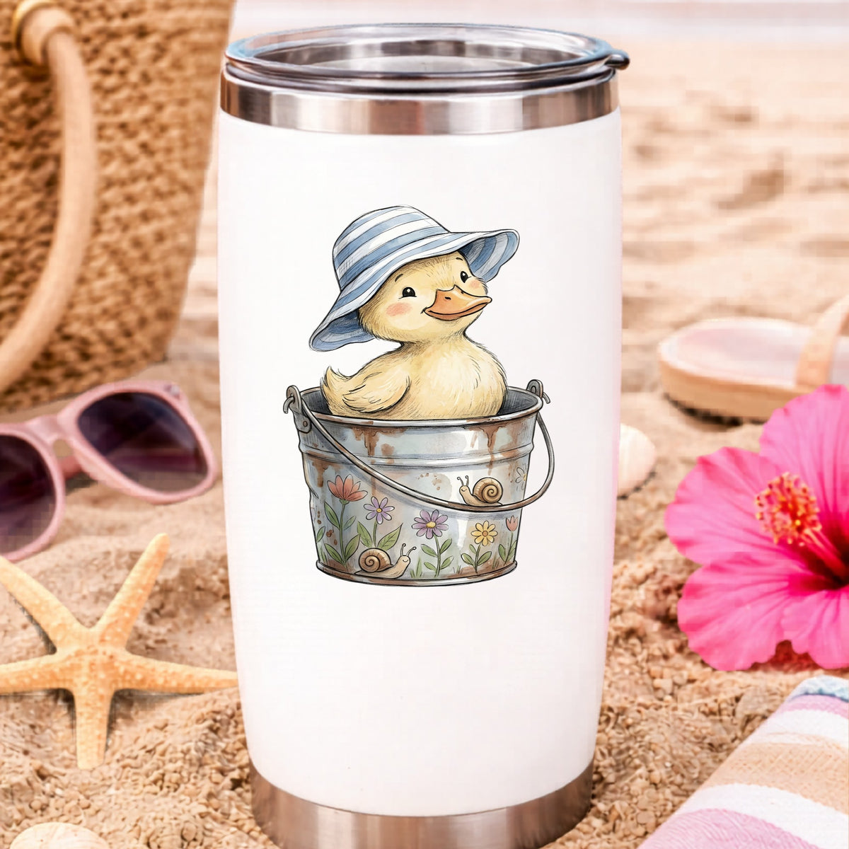 Duckling In Sun Hat In Bucket UV DTF sticker applied to a white travel tumbler on beach sand