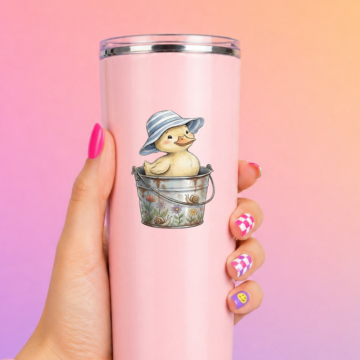 Duckling In Sun Hat In Bucket UV DTF sticker applied to a tall pink tumbler on a pink and orange background