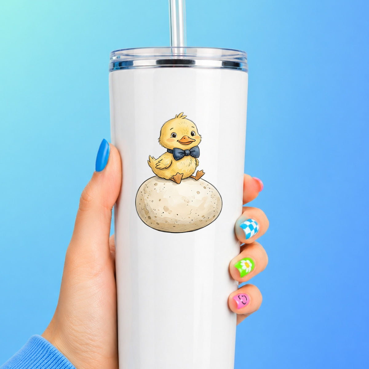 Duckling On Giant Egg UV DTF sticker applied to a white straw tumbler on a blue background